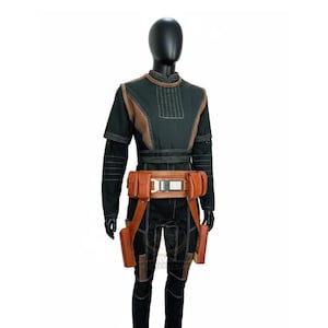 May include: A black long-sleeved tunic and pants set featuring white topstitching, brown textured shoulder panels, and a brown utility belt with multiple pouches and a central metallic buckle, worn on a black mannequin display form.