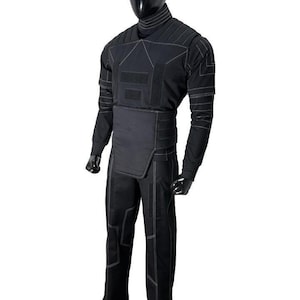 May include: Black tactical suit with white stitching, displayed on a mannequin. The suit includes a long-sleeved top, pants, and a high collar. The design features reinforced panels and a streamlined silhouette, suitable for various activities.