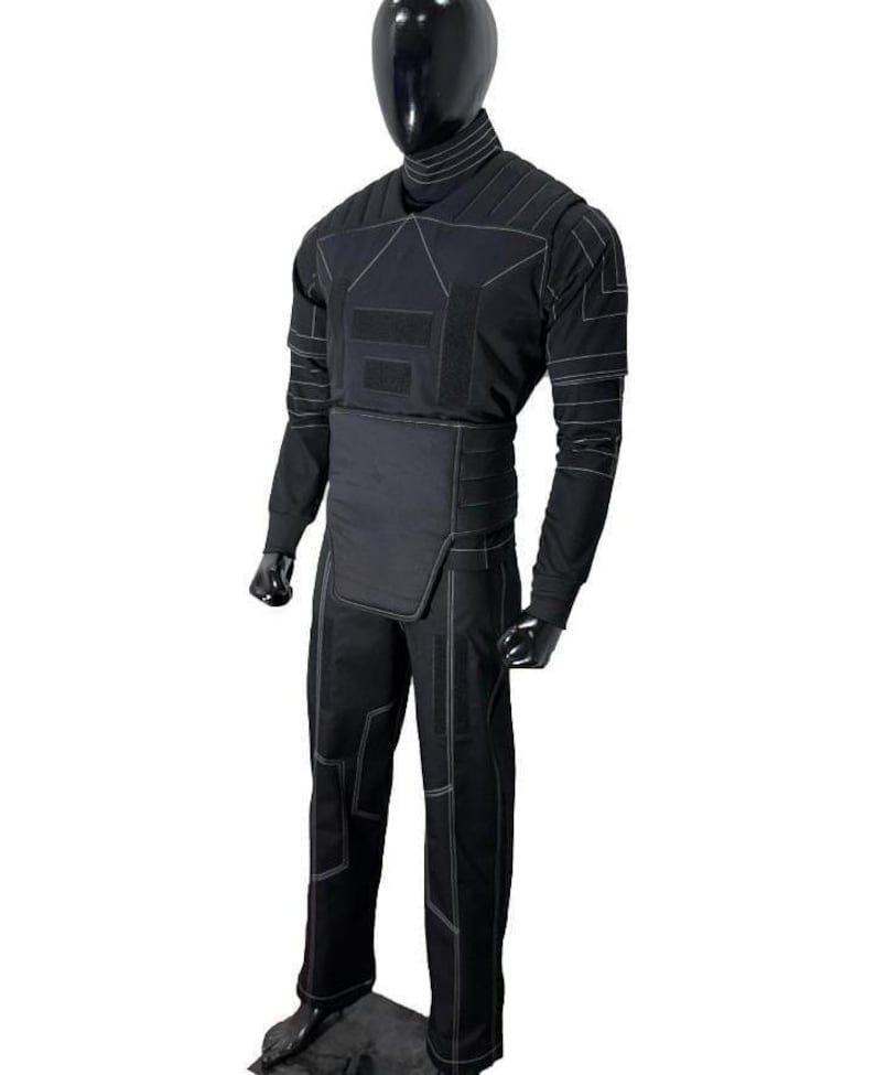 May include: Black tactical suit with white stitching, displayed on a mannequin. The suit includes a long-sleeved top, pants, and a high collar. The design features reinforced panels and a streamlined silhouette, suitable for various activities.