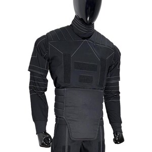 May include: Black tactical suit displayed on a mannequin. The suit features a high collar, long sleeves, and reinforced panels with white stitching. The design includes multiple hook-and-loop fastener patches and a padded lower torso section.