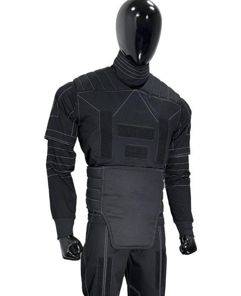 May include: Black tactical suit displayed on a mannequin. The suit features a high collar, long sleeves, and reinforced panels with white stitching. The design includes multiple Velcro patches and a padded lower torso section. The mannequin has a black, reflective head.