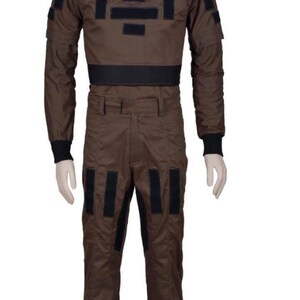 May include: Brown jumpsuit with black accents. The one-piece garment features a high collar, long sleeves, and multiple black rectangular patches on the chest, shoulders, and legs. The jumpsuit has a black belt and cuffs.