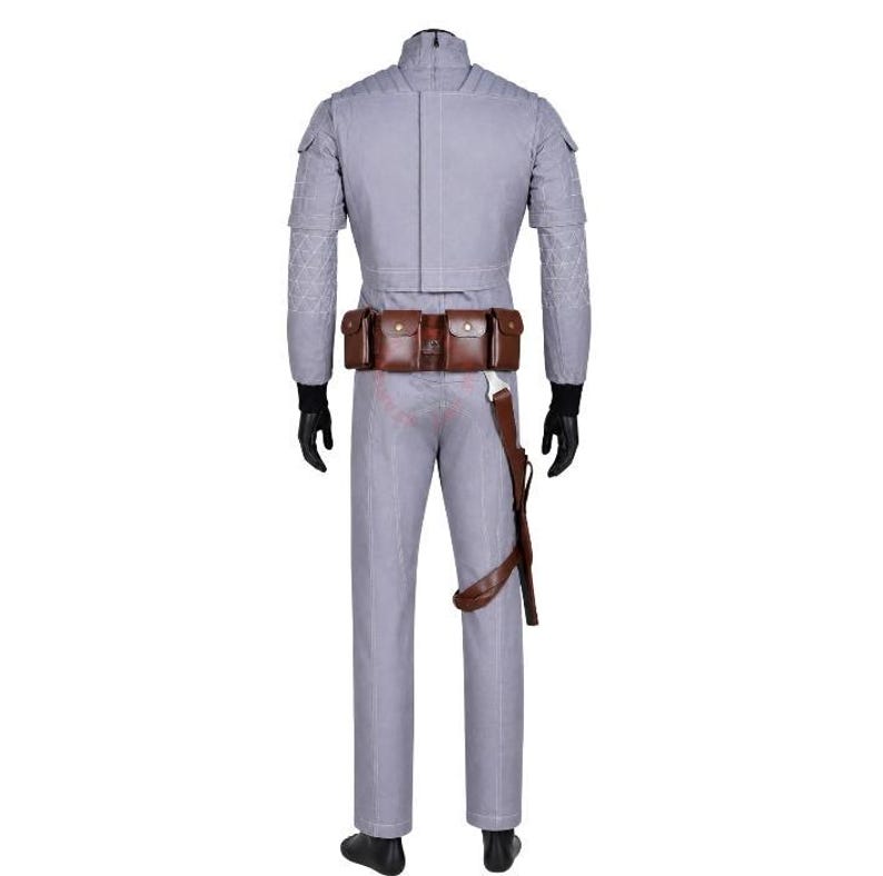 May include: A light grey long-sleeved jumpsuit featuring quilted shoulder and sleeve detailing, a high collar, and black gloves. A brown leather utility belt with multiple pouches and a holster is worn around the waist over the jumpsuit.