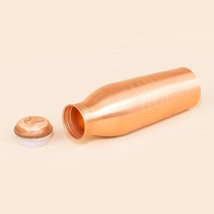 May include: A copper-coloured water bottle with a matching lid. The bottle is cylindrical with a narrow neck and a wide opening. The lid is round with a white interior. The bottle is lying on its side, with the lid next to it.
