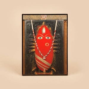 Puede incluir: Icono religioso rojo ovalado enmarcado, con ojos azules y un collar a rayas blanco y rojo. El icono está sobre un fondo oscuro con detalles dorados y un marco negro. Un pequeño símbolo en la parte superior.