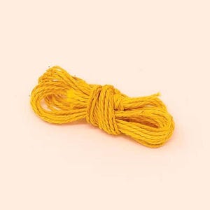 Puede incluir: Un rollo de hilo amarillo, enrollado y anudado. El hilo es de un color amarillo mostaza vibrante y parece estar hecho de fibras naturales. El fondo es de un color blanco roto suave.