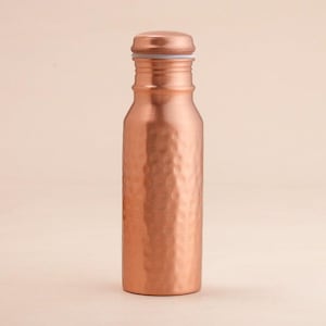 May include: A copper-coloured water bottle with a hammered texture. The bottle has a rounded body and a screw-on cap. The design is simple and elegant, suitable for everyday use. The bottle is made of metal.