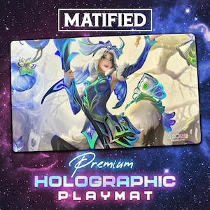 May include: Premium holographic playmat featuring a fantasy illustration of a female character with white hair and blue and green attire. The playmat has the text "MATIFIED" and "Premium Holographic Playmat".