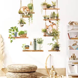 May include: Watercolor wall decals featuring hanging shelves with potted plants and adorable orange and white cats. The design includes various green plants and wooden shelves, creating a charming, whimsical aesthetic for home decor.