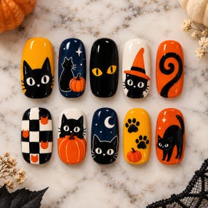 May include: A set of ten press-on nails featuring Halloween-themed designs. The nails display black cats, orange pumpkins, paw prints, a checkered pattern, a crescent moon, and stars against yellow, navy blue, black, white, and orange backgrounds.