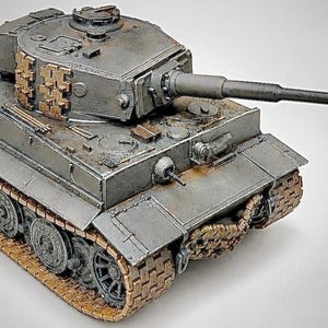 May include: A scale model of a gray tank featuring a long barrel, a rotating turret with attached track links, and detailed metallic brown treads. The tank body displays weathered textures, a front-mounted machine gun, and a hatch on the turret top.