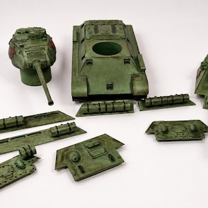 May include: A collection of olive green plastic model tank parts, including a main hull, two distinct turret styles with long barrels, and various side panels and armor plates. Each piece features a weathered finish with red star markings.