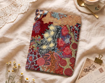 May include: A rectangular notebook featuring a vibrant, intricate dot-art pattern in shades of red, yellow, black, and blue. The design includes circular motifs, star-like shapes, and flowing lines that cover the entire front cover surface.