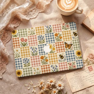 May include: A laptop skin featuring a grid of colorful gingham squares in yellow, blue, green, and pink, interspersed with illustrations of various wildflowers, bees, and a butterfly, centered around a cutout for an Apple logo.