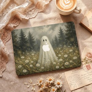 May include: A rectangular laptop skin featuring a dark, moody forest landscape with a central white ghost figure. The ghost incorporates a cutout for an Apple logo. The scene includes a field of white daisies under a cloudy, overcast sky.
