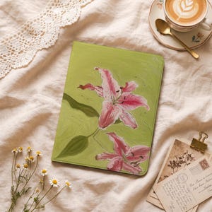 Peut inclure: Une coque de tablette rectangulaire ornée d'une peinture représentant deux lys roses tachetés sur un fond vert clair. L'illustration présente des coups de pinceau visibles et des feuilles vertes, donnant un aspect texturé à la protection.