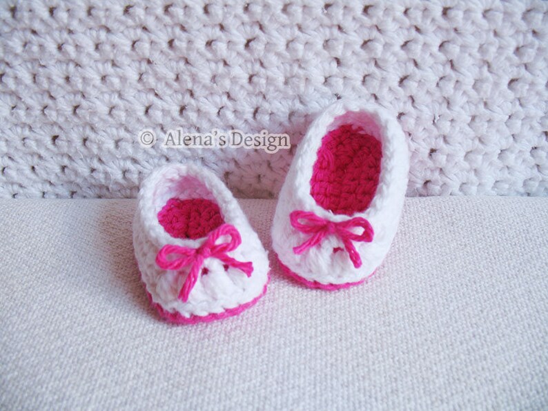 Puede incluir: Un par de zapatos de beb&eacute; de ganchillo blanco con lazos rosas y ribete rosa.