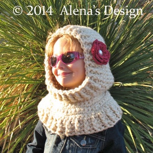 May include: A beige crocheted hood with a burgundy flower and a silver center. The hood is worn over a denim jacket. The text "&copy; 2014 Alena's Design" is visible in the upper left corner.