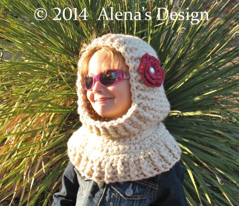 May include: A beige crocheted hood with a burgundy flower and a silver center. The hood is worn over a denim jacket. The text "&copy; 2014 Alena's Design" is visible in the upper left corner.