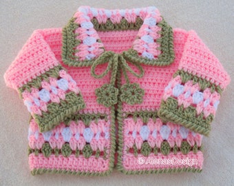 May include: A pink crocheted baby cardigan with green and white trim. The cardigan has a small bow at the neckline and a flower design on the front.
