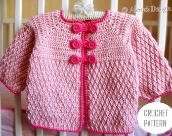May include: Pink crocheted baby cardigan with a diamond stitch pattern and pink buttons. The cardigan has a pink crocheted border.