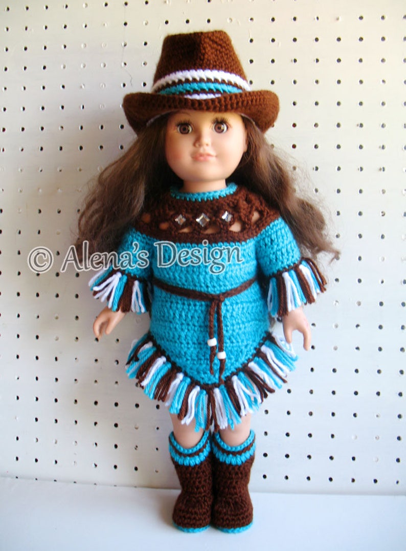 May include: A crocheted doll outfit in turquoise, brown, and white. The outfit includes a dress with fringe, a hat, and boots. The doll is wearing the outfit and has brown hair.