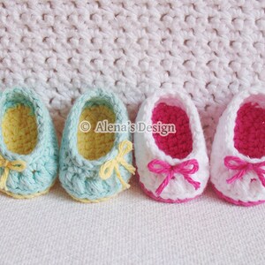 Puede incluir: Dos pares de zapatos de beb&eacute; tejidos a crochet. Un par es blanco con ribetes y lazos rosas, el otro es azul claro con ribetes y lazos amarillos.  "Alena's Design" est&aacute; escrito en la imagen.
