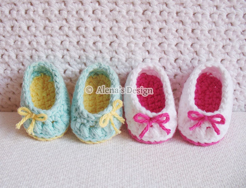 Puede incluir: Dos pares de zapatos de beb&eacute; tejidos a crochet. Un par es blanco con ribetes y lazos rosas, el otro es azul claro con ribetes y lazos amarillos.  "Alena's Design" est&aacute; escrito en la imagen.