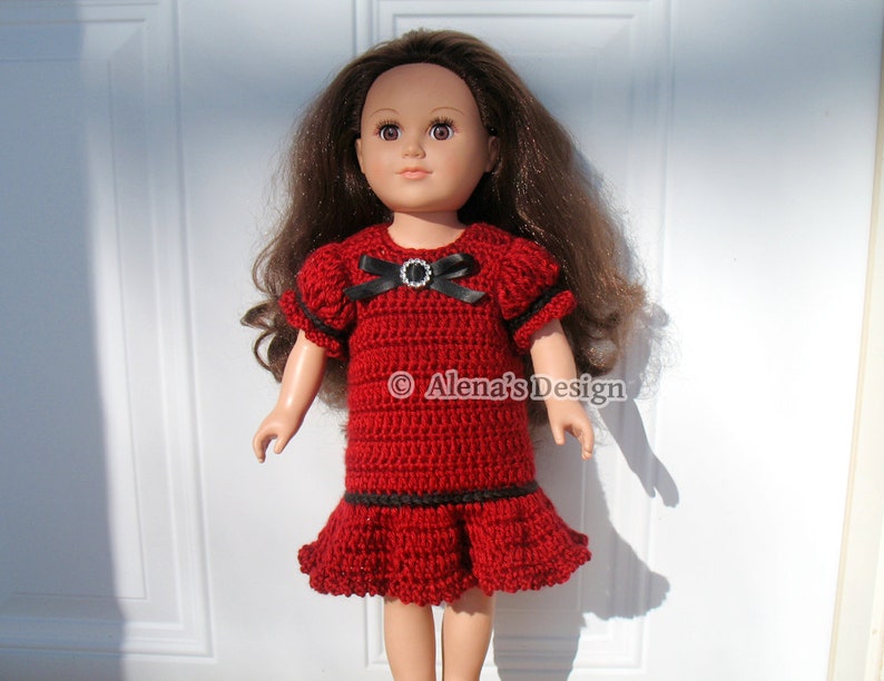 May include: A red crochet dress with black trim and a black bow with a rhinestone embellishment. The dress is worn by a doll with brown hair.