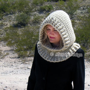 May include: A beige crocheted hood and cowl set. The hood features a ribbed design and a rounded top, connected to a cowl that fits around the neck. The set is made of a thick, textured yarn. The text "Alena's Design" is visible.