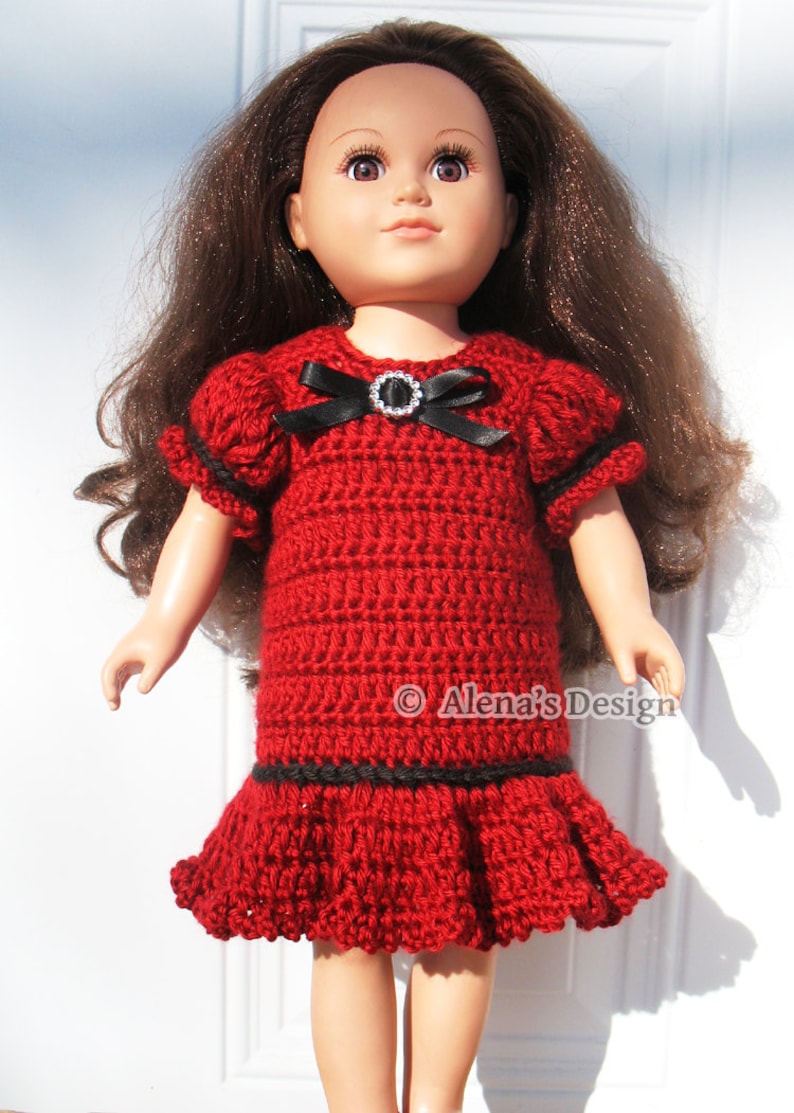 May include: A red crochet dress with black trim and a black bow with a rhinestone embellishment. The dress is designed for a doll.
