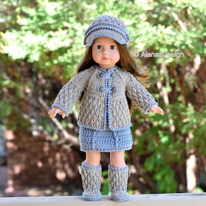 May include: A doll wearing a crocheted outfit in shades of brown and blue. The outfit includes a cardigan, skirt, hat, and boots. The doll has long brown hair and blue eyes. The text "AlenasDesign" is visible in the image.