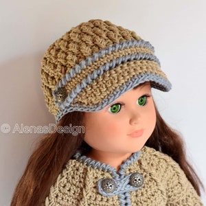 May include: A doll wearing a crocheted hat with a brim and a matching crocheted jacket. The hat is brown with a blue trim and the jacket has a blue trim and buttons.