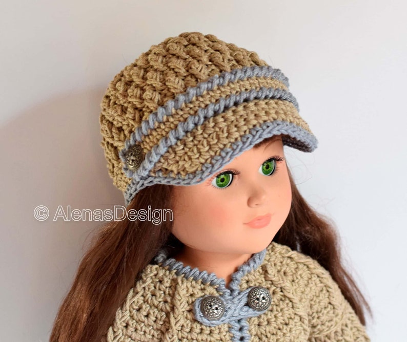 May include: A doll wearing a crocheted hat with a brim and a matching crocheted jacket. The hat is brown with a blue trim and the jacket has a blue trim and buttons.