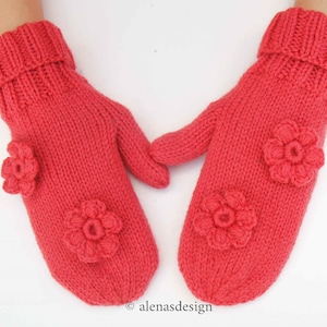 May include: A pair of coral pink knitted mittens with crocheted flower embellishments.