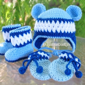 May include: A blue and white crocheted baby hat with ear flaps and matching booties and mittens. The hat has a white stripe pattern and the booties and mittens have a blue and white stripe pattern.