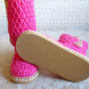 Puede incluir: Botas de crochet rosa con suela marr&oacute;n y detalle de bot&oacute;n de madera. &copy; Alena's Design