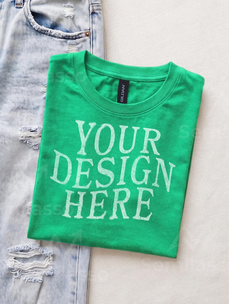 May include: A bright green short-sleeved t-shirt with a crew neckline and a black Gildan brand label at the collar. The front of the shirt features the white distressed-style text that reads YOUR DESIGN HERE in a bold, capitalized font.