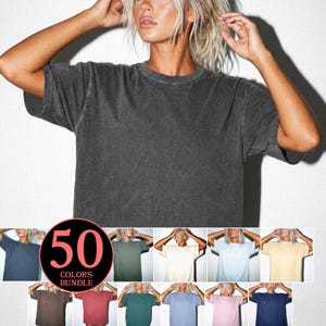 May include: Dark gray, short-sleeved t-shirt. The image shows a variety of t-shirts in different colors. The text "50 COLORS BUNDLE" is displayed in a circle. The t-shirts are displayed on a model.