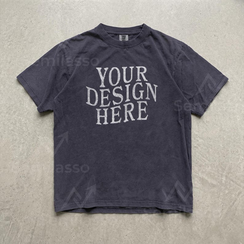 May include: A dark charcoal gray short-sleeve t-shirt with a crew neckline. The center of the chest features the white text "YOUR DESIGN HERE" in a distressed, serif font. The fabric has a slightly faded, washed-out appearance throughout.