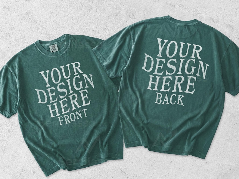 May include: Two dark teal short-sleeve t-shirts displayed together. The left shirt features the white text YOUR DESIGN HERE FRONT. The right shirt displays the white text YOUR DESIGN HERE BACK. Both garments have a crew neckline and a relaxed fit.