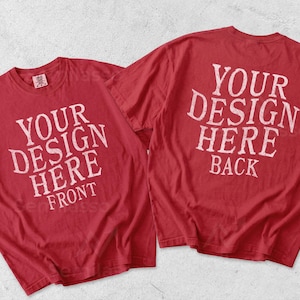 May include: Two red short-sleeve t-shirts displayed together. The left shirt features the white text 'YOUR DESIGN HERE FRONT', and the right shirt features the white text 'YOUR DESIGN HERE BACK'. Both shirts have a crew neckline and a standard fit.