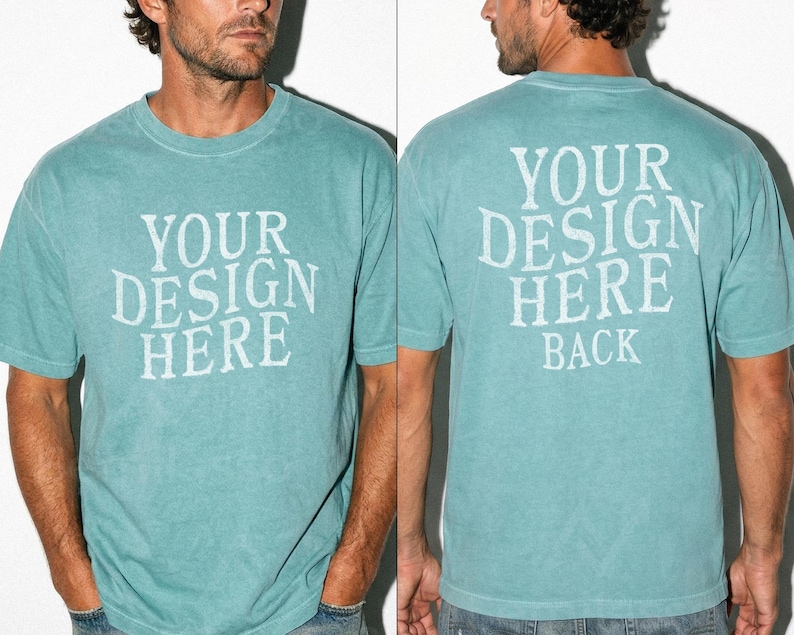 May include: A teal-colored t-shirt with the text "YOUR DESIGN HERE" printed on the front and "YOUR DESIGN HERE BACK" on the back. The shirt has short sleeves and a crew neck. The fabric appears to be slightly faded.