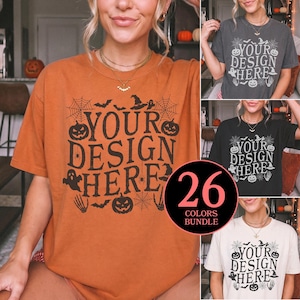 May include: A short-sleeve t-shirt featuring a black graphic print with the text YOUR DESIGN HERE surrounded by Halloween motifs including jack-o'-lanterns, spiderwebs, bats, ghosts, and skeletons. The shirt is available in multiple colors.