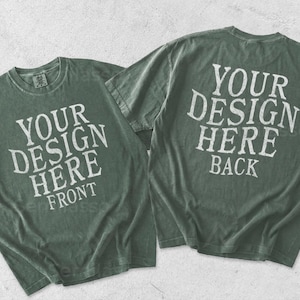 May include: Two sage green short-sleeve t-shirts displayed flat. The left shirt features the white text YOUR DESIGN HERE FRONT. The right shirt displays the white text YOUR DESIGN HERE BACK. Both garments have a crew neckline and a vintage wash.