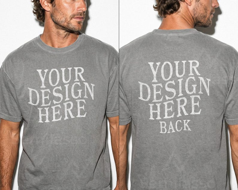 May include: A gray t-shirt with the text "YOUR DESIGN HERE" printed on the front and back in a distressed white font. The shirt has a crew neck and short sleeves. The fabric appears to be pre-washed.