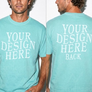 May include: A light turquoise t-shirt with the text "YOUR DESIGN HERE" printed on the front and "YOUR DESIGN HERE BACK" on the back. The shirt is a crew neck style and appears to be made of a soft material.