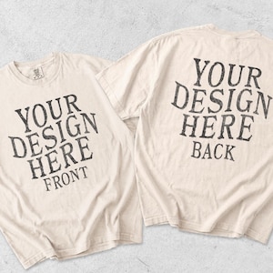 May include: Two off-white short-sleeve t-shirts displayed together. The left shirt features dark gray text reading YOUR DESIGN HERE FRONT. The right shirt features dark gray text reading YOUR DESIGN HERE BACK. Both shirts have a crew neckline.