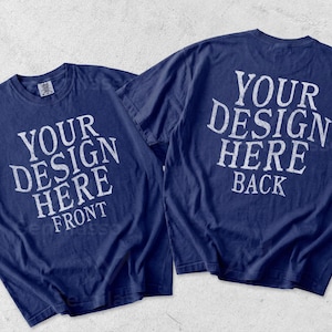 May include: Two navy blue short-sleeve t-shirts displayed side by side. The left shirt features white text reading YOUR DESIGN HERE FRONT. The right shirt features white text reading YOUR DESIGN HERE BACK. Both shirts have a crew neckline.