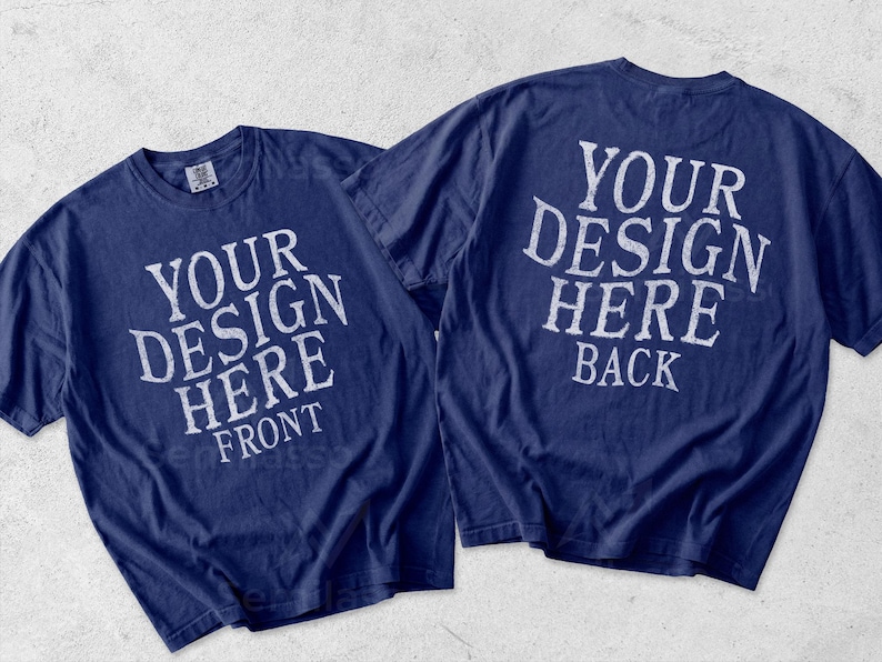 May include: Two navy blue short-sleeve t-shirts displayed side by side. The left shirt features white text reading YOUR DESIGN HERE FRONT. The right shirt features white text reading YOUR DESIGN HERE BACK. Both shirts have a crew neckline.